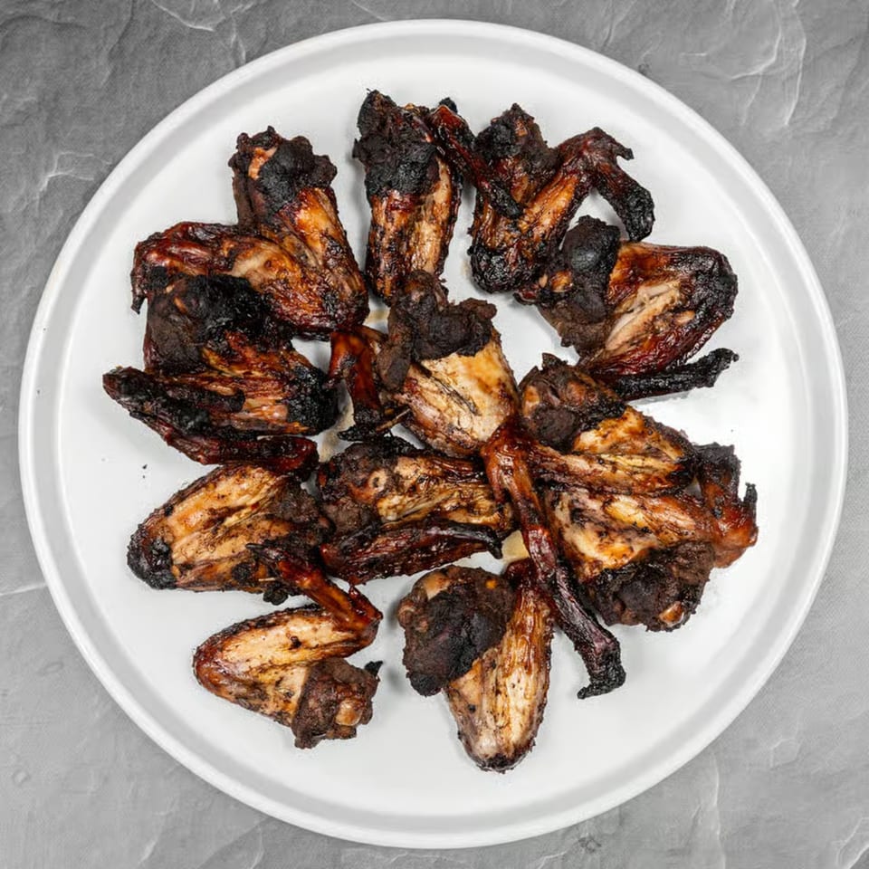 A white plate filled with Jerk Villa Bar & Grill's Jamaican jerk chicken wings.